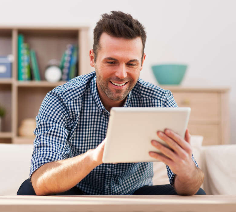 Smiling handsome man using digital tablet at home